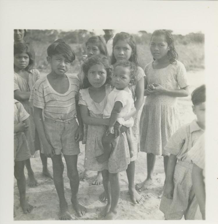 Image of Black and white print of a group of children with a girl holding a baby